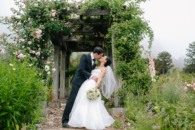Bride and groom standing in rose arbor at their UC Berkeley Botanical Garden Wedding