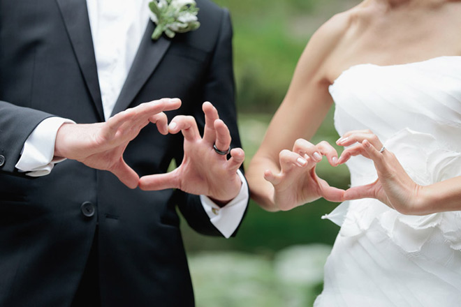 Bride and groom making love gesture with their hands