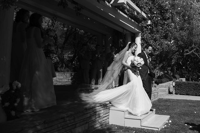 Carmel wedding photo of bride and groom standing under rose arbor