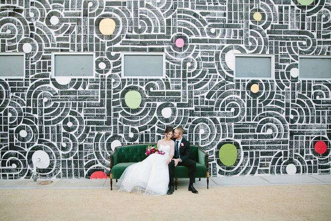 wedding couple sitting on sofa in front of a mural at the Ace Hotel in Palm Springs
