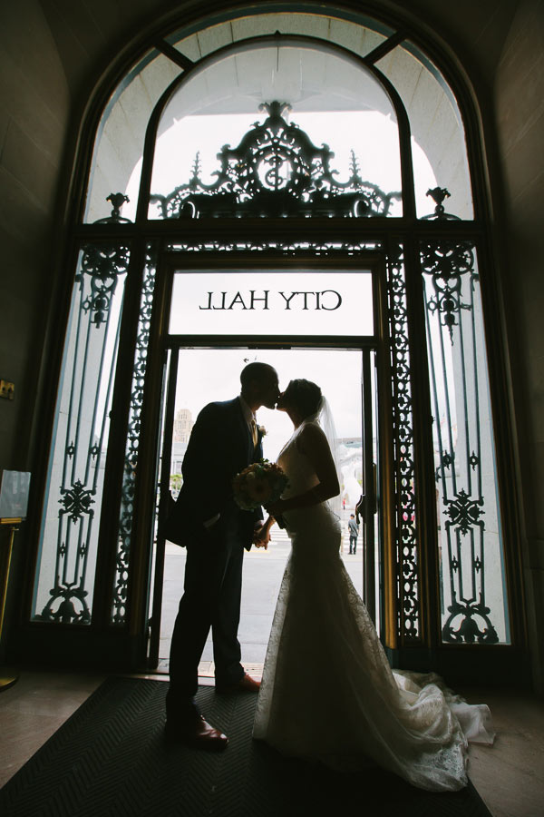 Silhouette photo of bride and groom standing in doorway of SF City Hall
