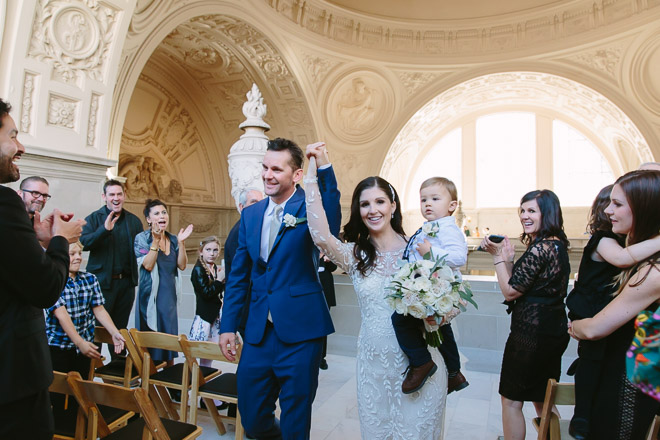 San Francisco wedding
photographer, bride and groom and their son walk down the aisle together after their wedding ceremony at San Francisco City Hall