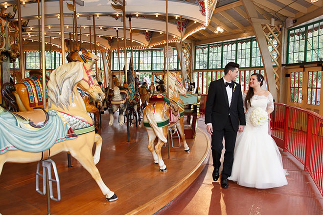 Bride and groom walking near the carousel at the San Francisco Zoo wedding